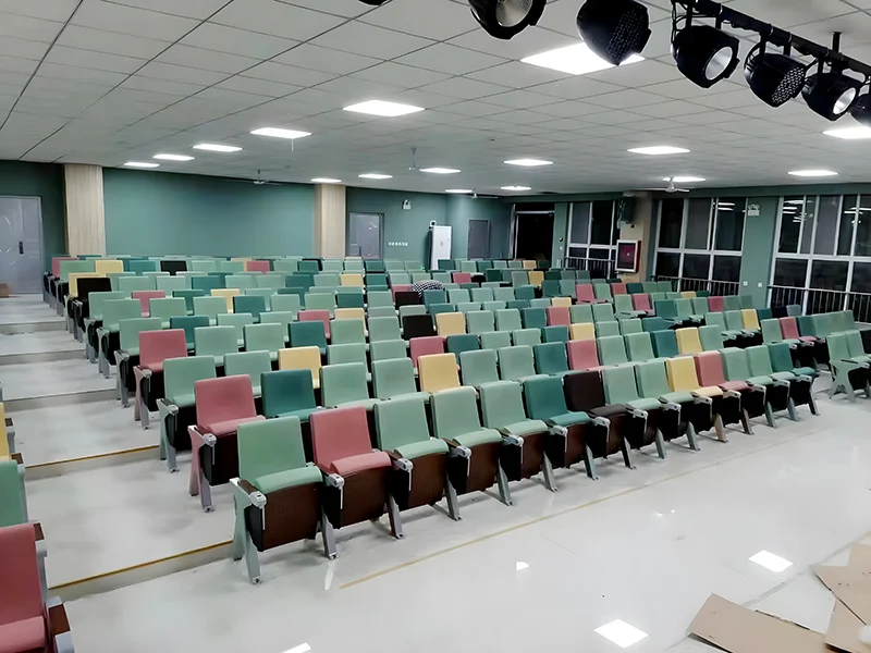 Auditorium chair with wider aisle arm for end of row installation.